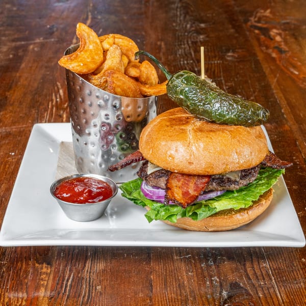 The Fields Bar & Grill's bacon cheeseburger with lettuce, onion, a jalapeño, fries, and ketchup.