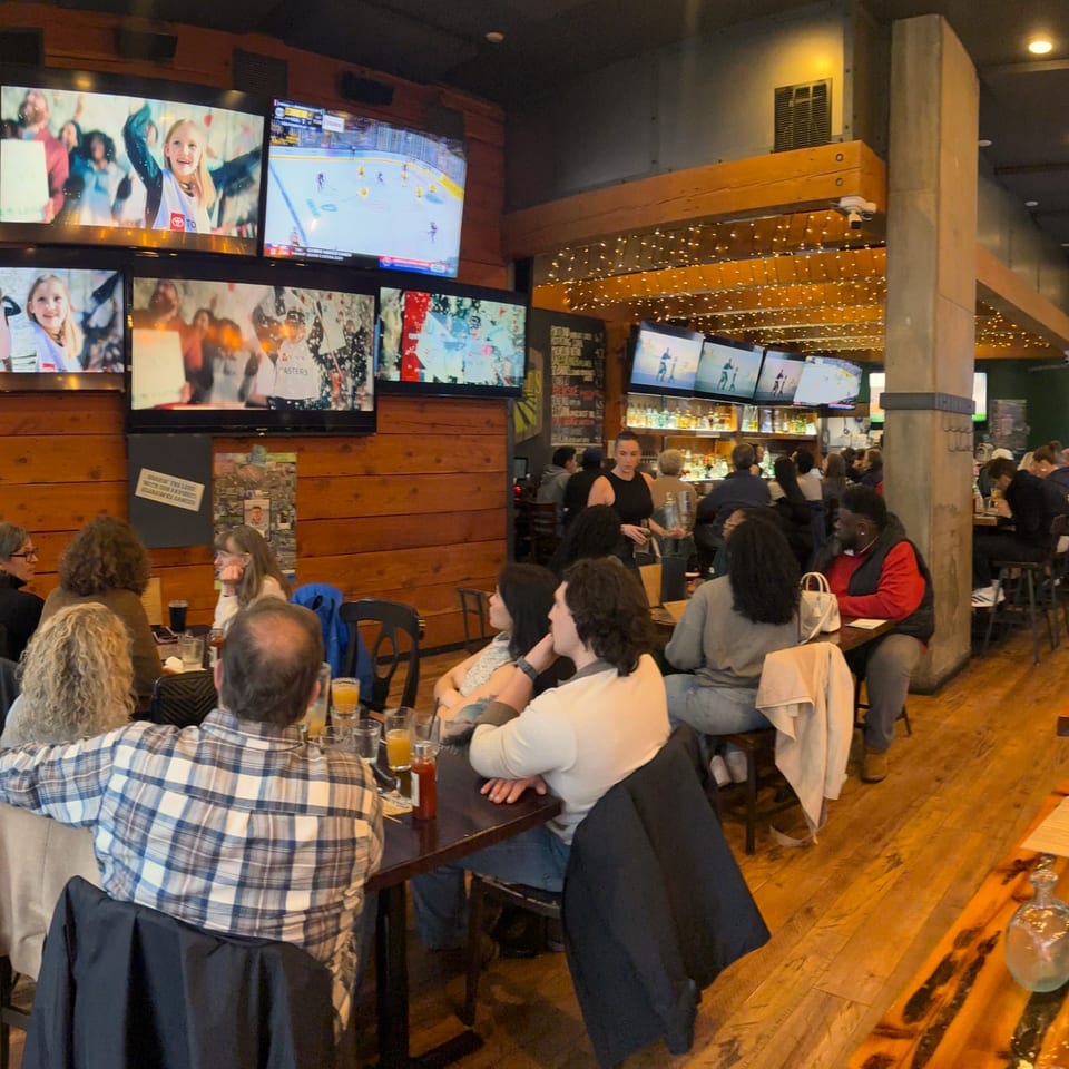 Diners and drinkers fill The Fields Bar & Grill, with multiple TVs showing sports and entertainment.