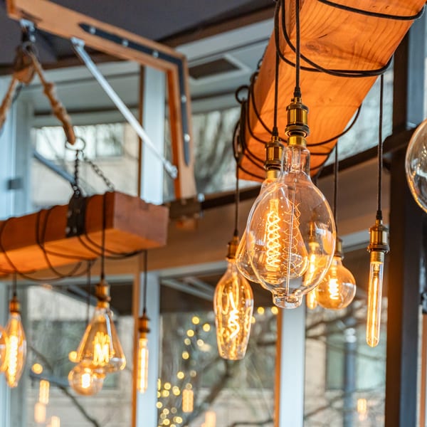 Close-up of vintage Edison-style light bulbs hanging from a wooden beam at The Fields Bar & Grill.