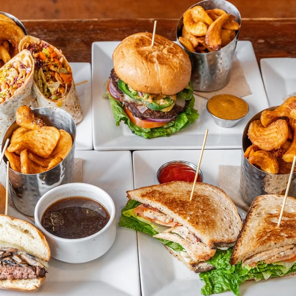 Assortment of The Fields Bar & Grill's dishes, including wraps, burgers, sandwiches, and fries.